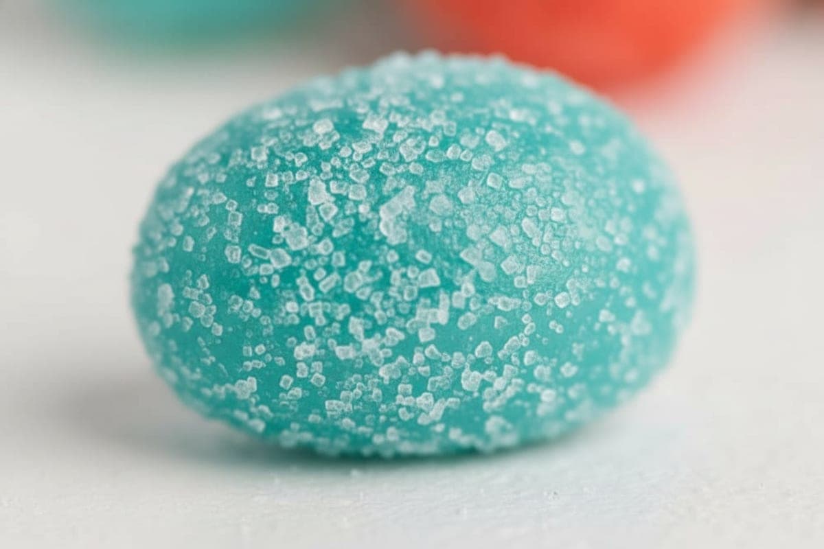 Close-up of a single red Jell-O coated grape showing glossy candy shell texture