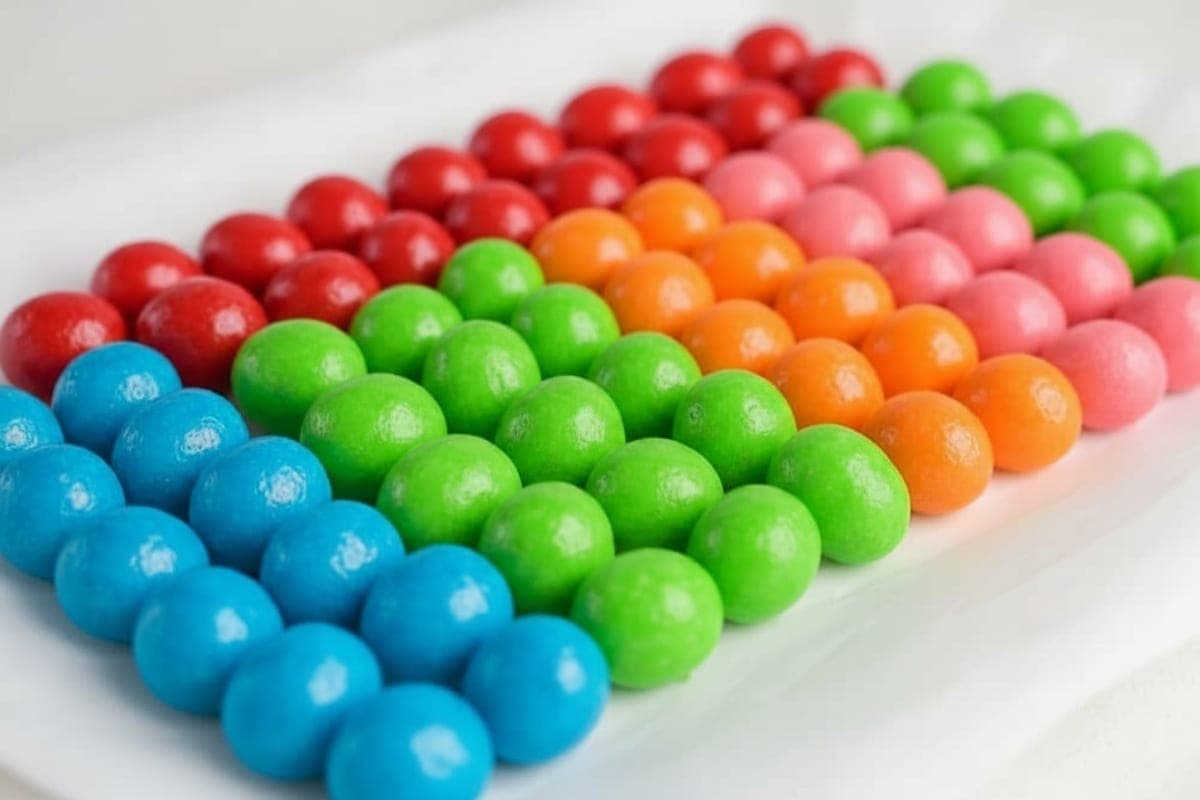 finished rainbow Jell-O candy grapes arranged by color on white parchment paper